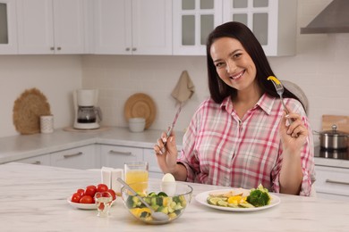 Photo of Beautiful overweight woman having healthy meal at table in kitchen