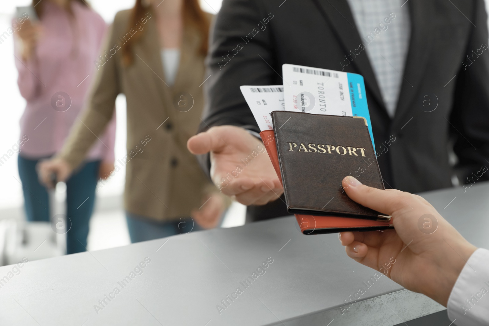 Photo of Agent giving passports and tickets to man at check-in desk in airport, closeup