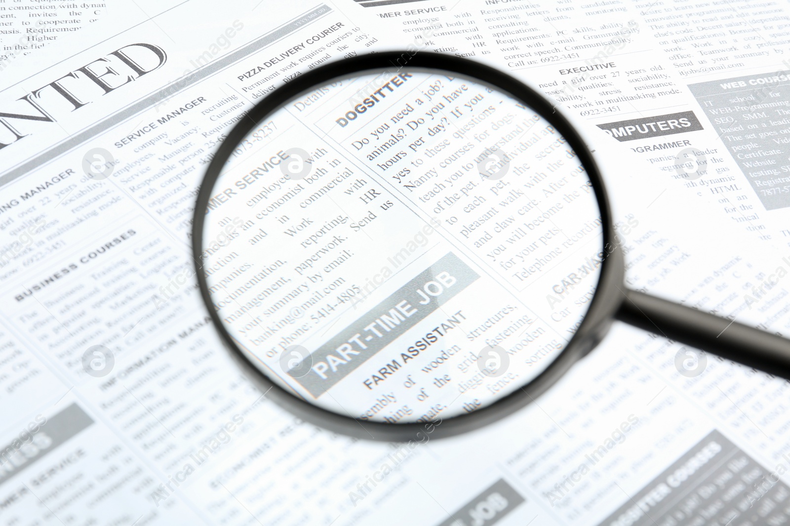 Photo of Looking through magnifying glass at newspaper, closeup. Job search concept