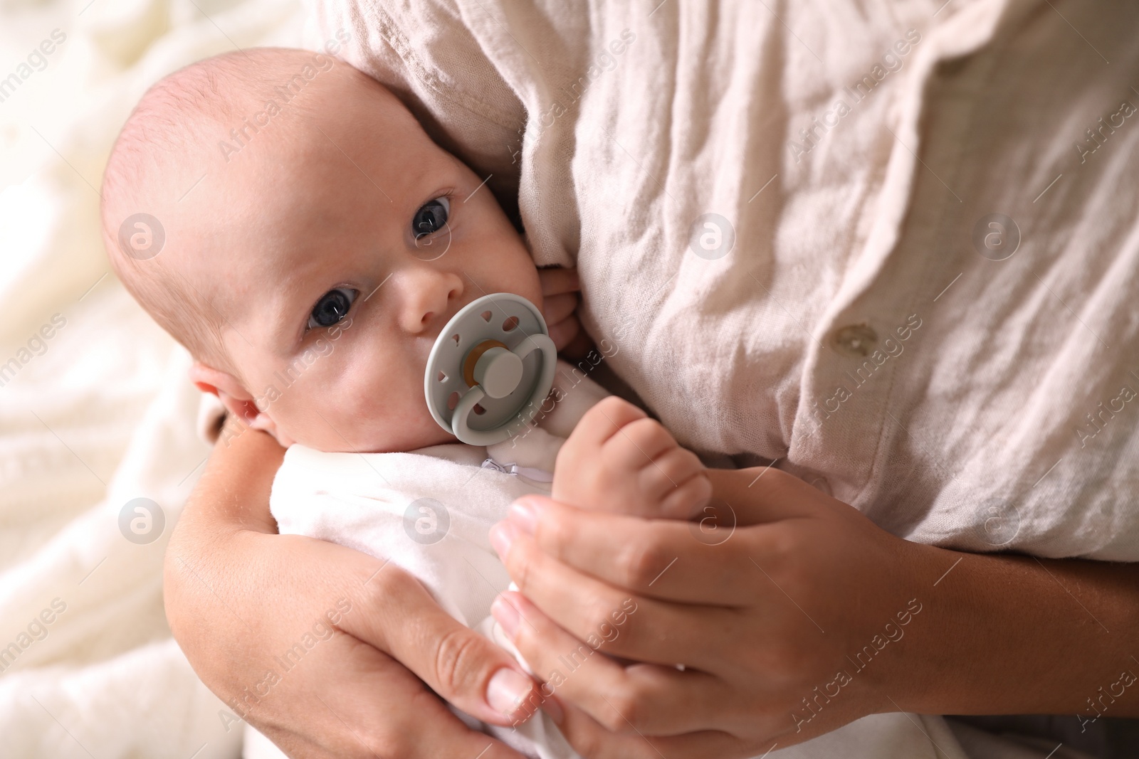 Photo of Mother hugging cute newborn baby on bed, closeup