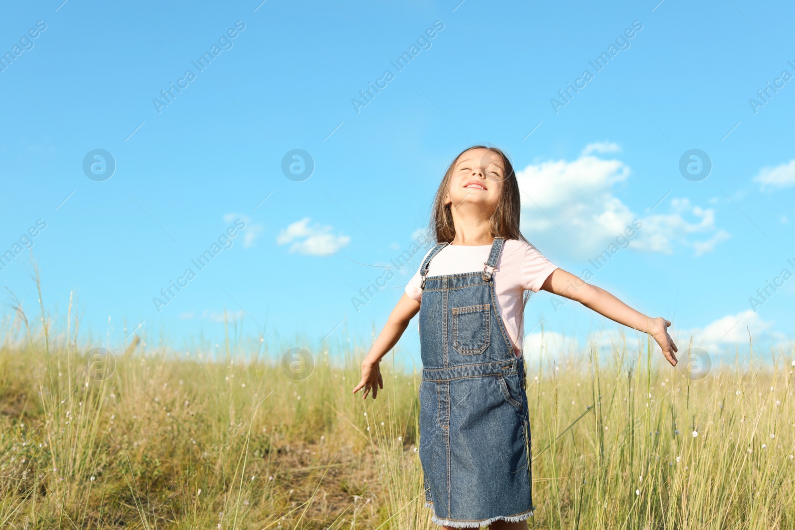 Photo of Cute little girl outdoors, space for text. Child spending time in nature