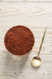 Photo of Delicious tiramisu in glass and spoon on light wooden table, top view