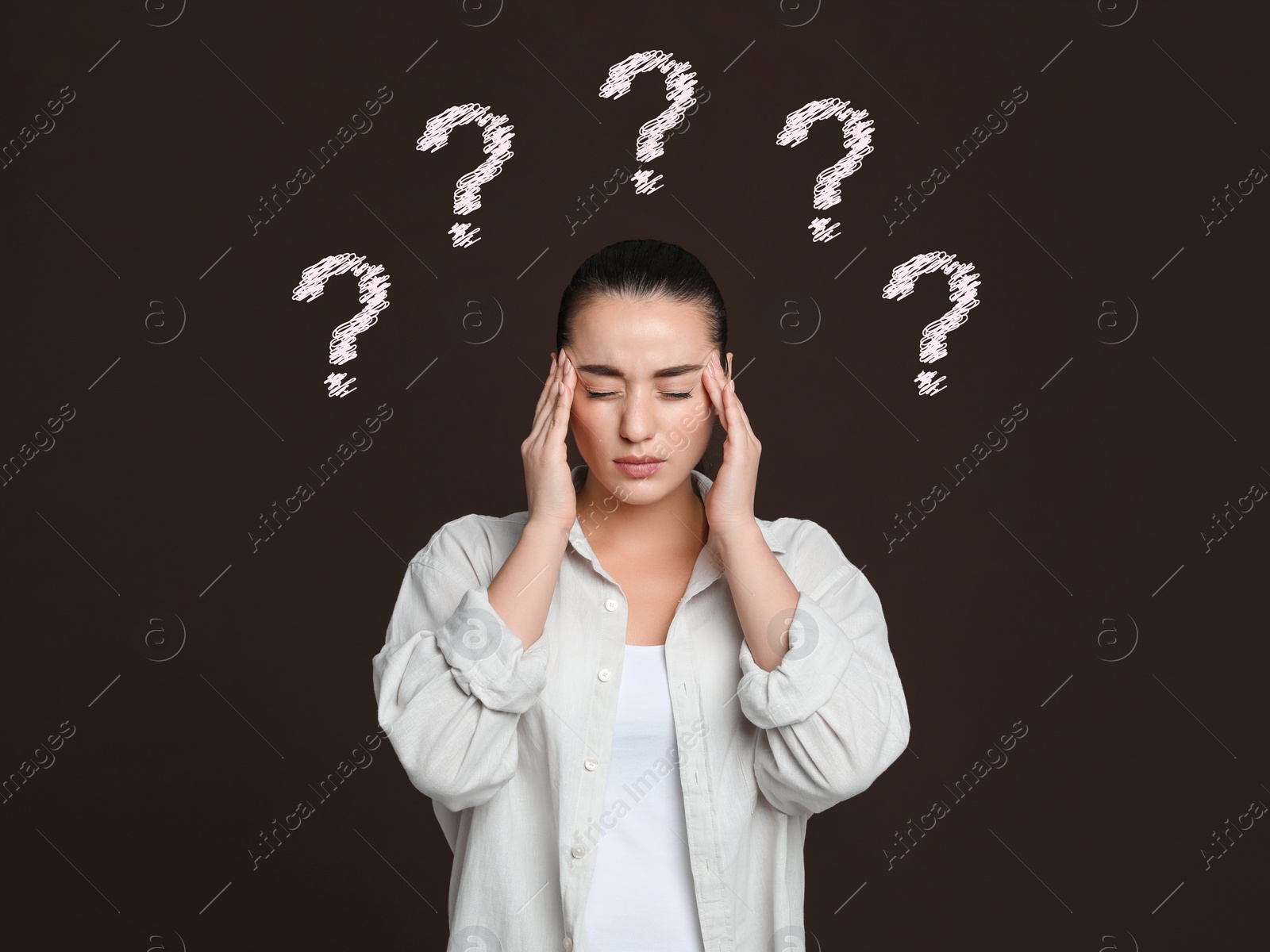 Image of Amnesia. Confused young woman and question marks on brown background