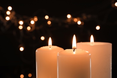 Wax candles burning against blurred lights in darkness