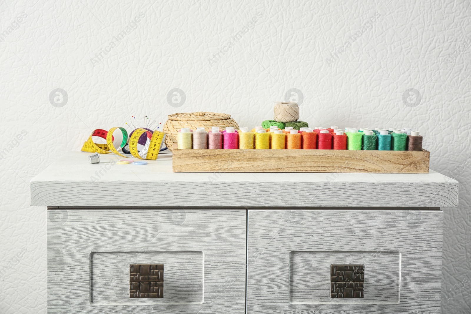 Photo of Wooden box with color sewing threads on cabinet