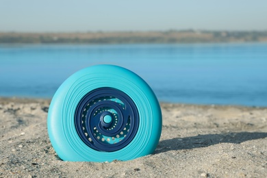Blue plastic frisbee disc on sandy beach near river
