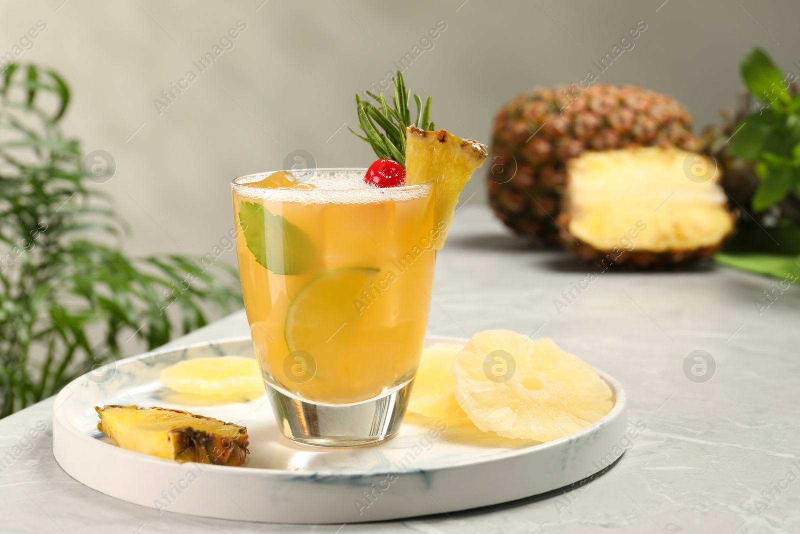 Photo of Glass of tasty pineapple cocktail and fresh fruit on light gray table