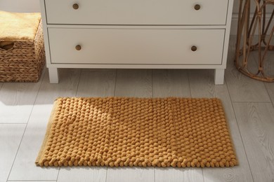 Stylish orange mat near chest of drawers in bathroom