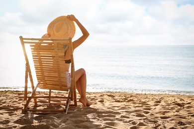 Woman relaxing on deck chair at sandy beach. Summer vacation