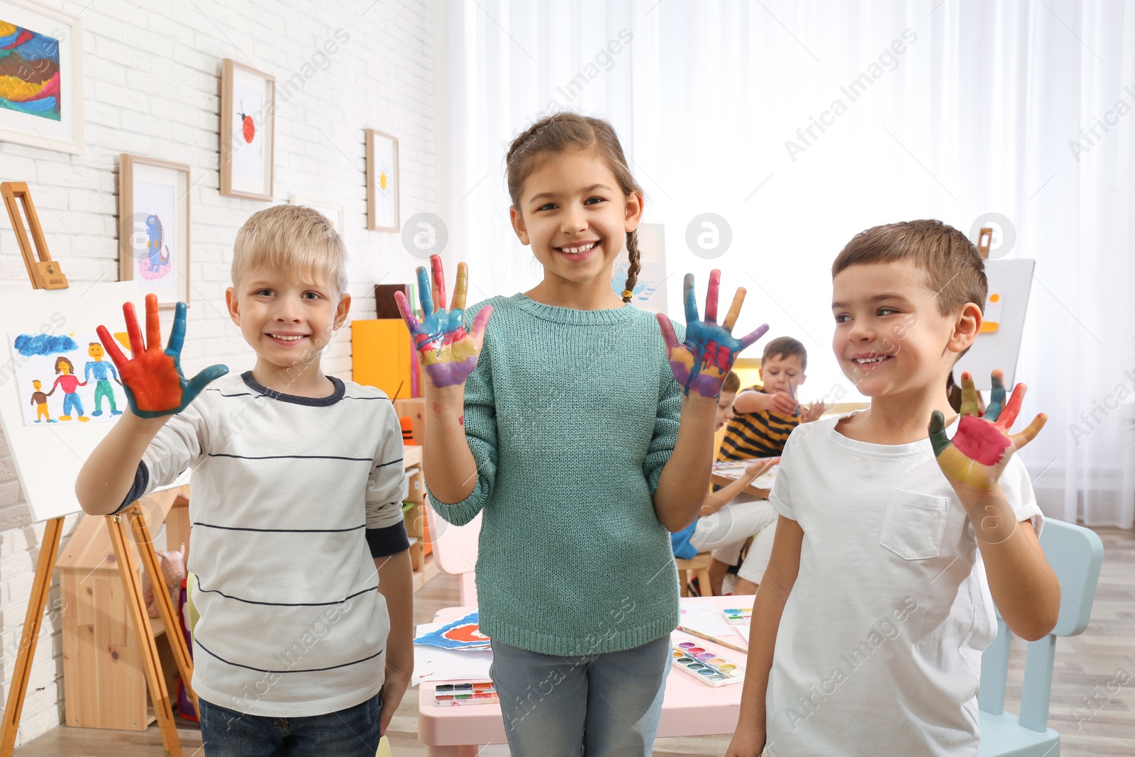 Photo of Cute little children with painted palms in room