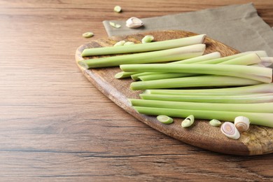 Photo of Board with fresh lemongrass stalks on wooden table. Space for text