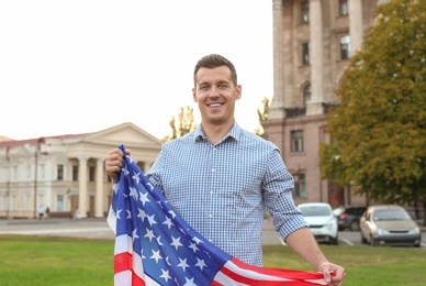 Man with American flag on city street