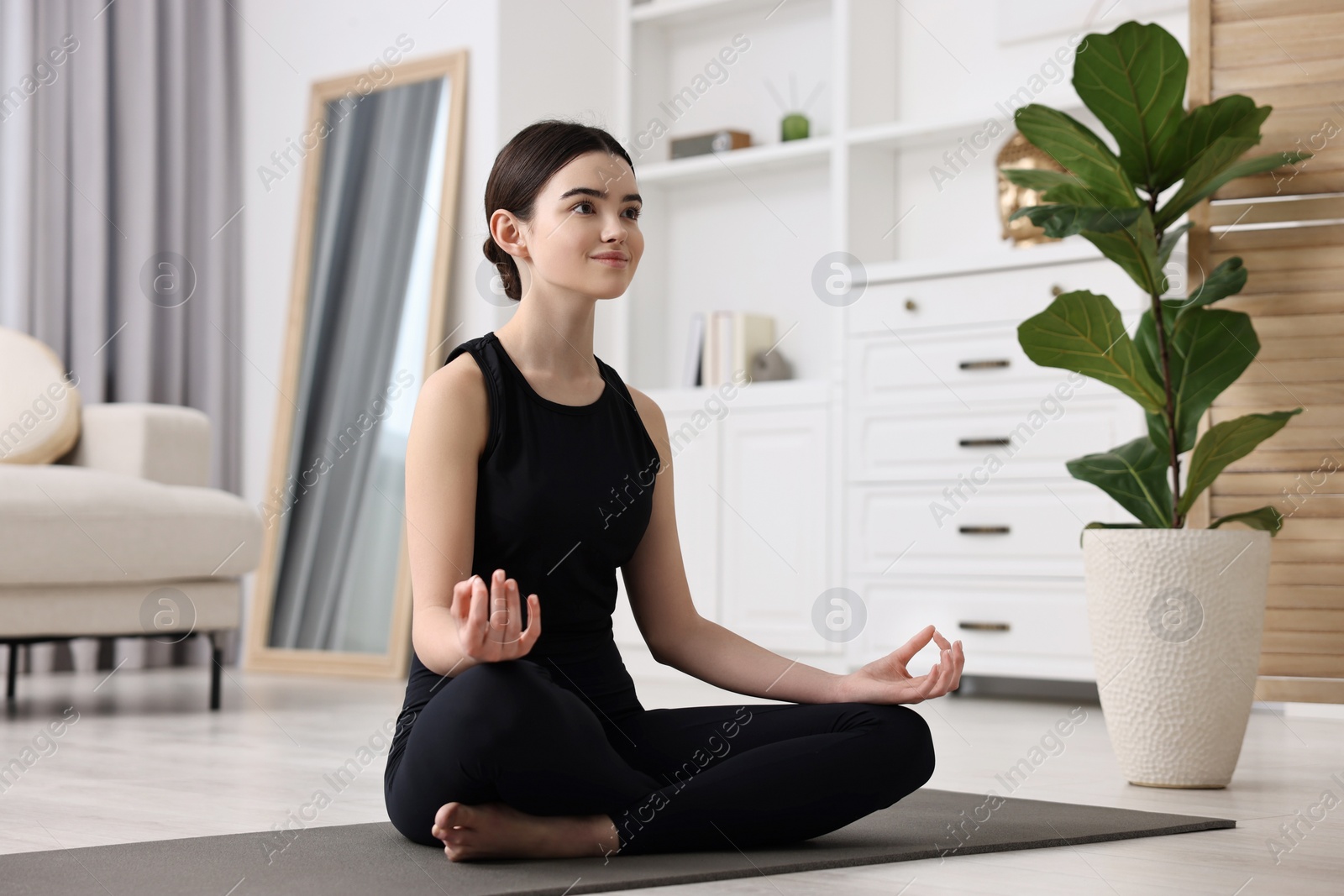 Photo of Beautiful girl meditating on yoga mat at home