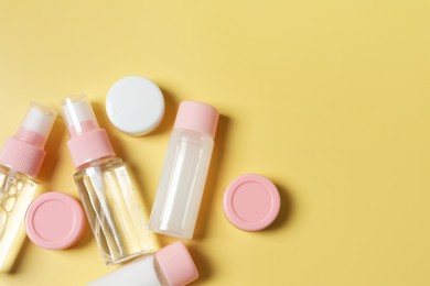 Photo of Cosmetic travel kit. Small containers of personal care products on yellow background, flat lay. Space for text