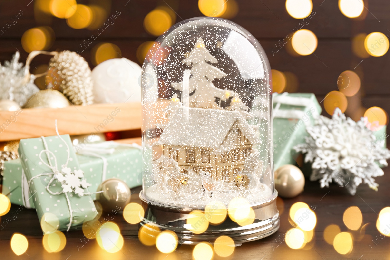 Image of Beautiful Christmas snow globe and festive decor on wooden table. Bokeh effect