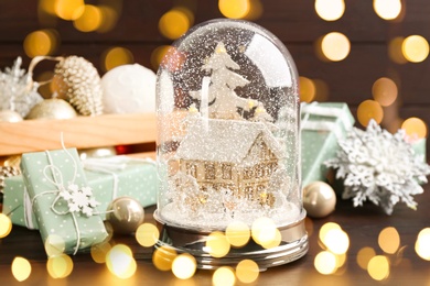 Image of Beautiful Christmas snow globe and festive decor on wooden table. Bokeh effect