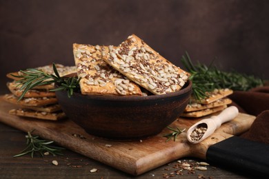 Photo of Cereal crackers with flax, sunflower, sesame seeds and rosemary on wooden table