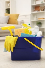 Photo of Different cleaning supplies in bucket on floor at home