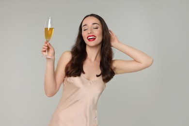 Photo of Christmas celebration. Beautiful young woman with glass of champagne on grey background