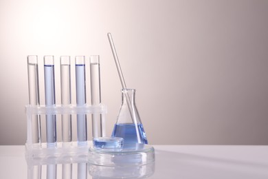 Photo of Laboratory analysis. Different glassware on table against light background, space for text