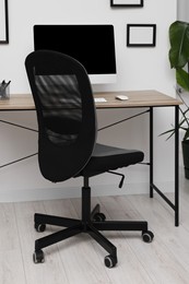 Photo of Comfortable office chair near desk in modern workplace