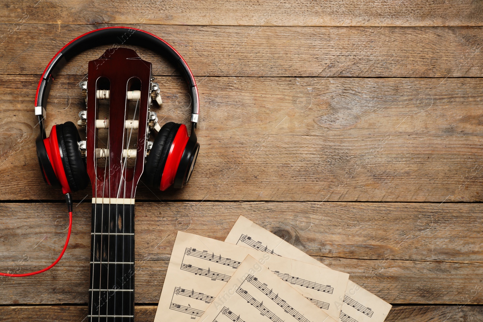 Photo of Composition with guitar and music notations on wooden table, flat lay. Space for text