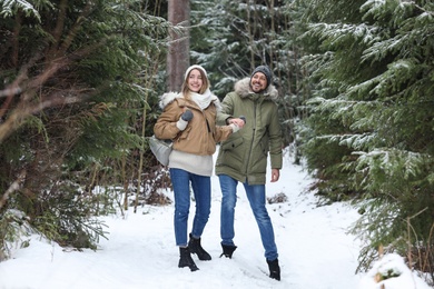 Couple in conifer forest on snowy day. Winter vacation