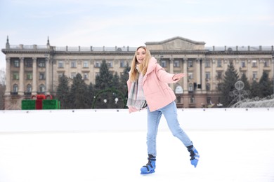 Image of Happy woman skating along ice rink outdoors