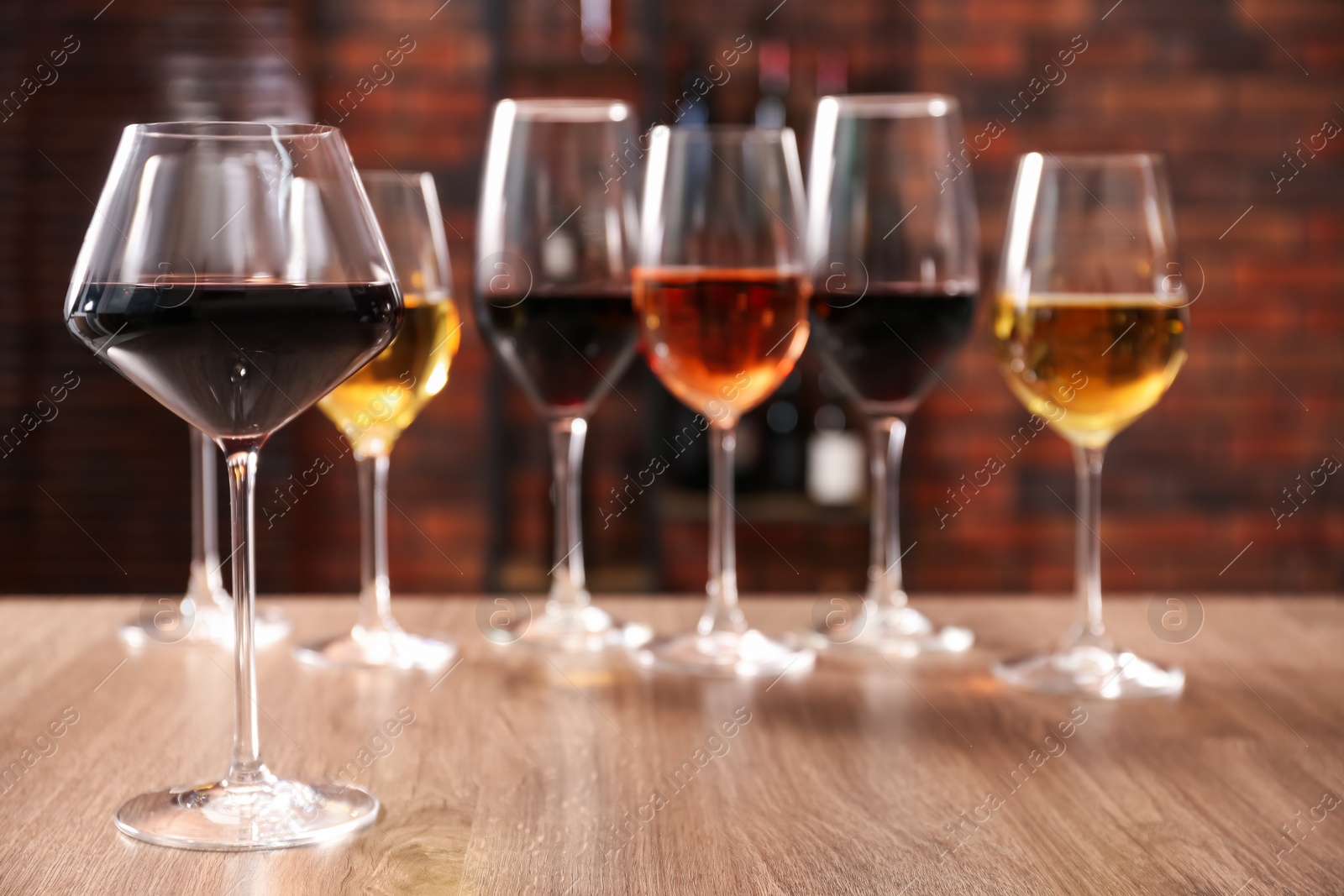 Photo of Different tasty wines in glasses on wooden table