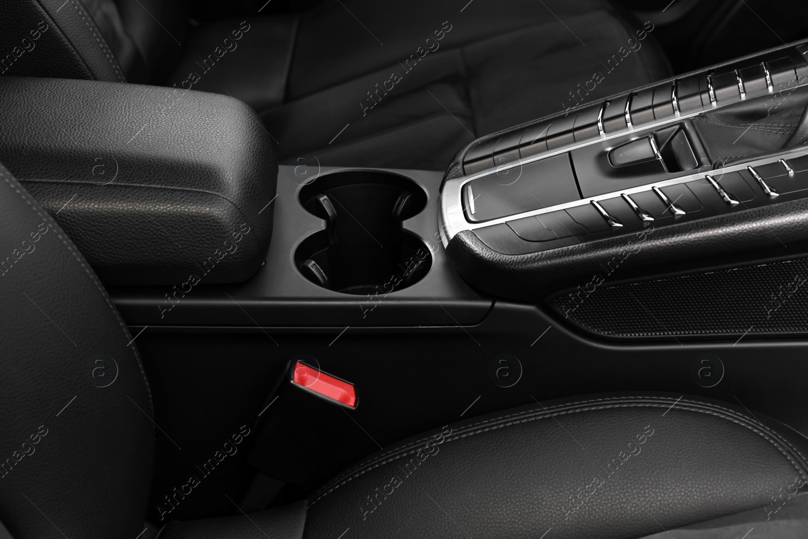 Photo of Cup holders and seat inside of modern black car, closeup