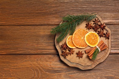 Photo of Composition with dry orange slices, anise stars, cinnamon sticks and fir branches on wooden table, flat lay. Space for text