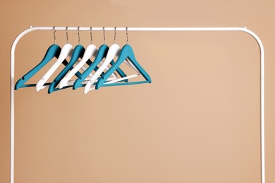 Photo of Clothes hangers on metal rack against beige background