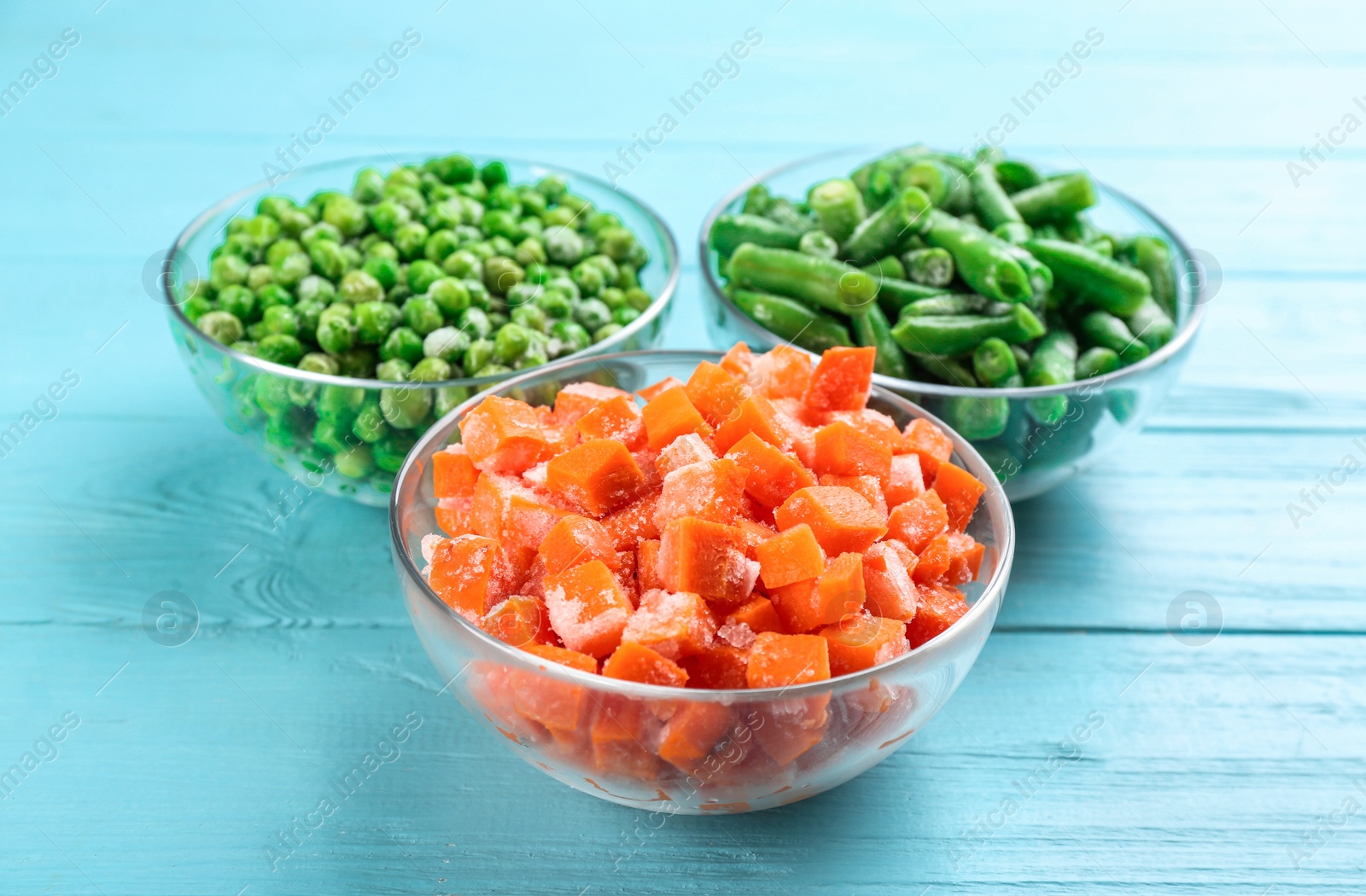 Photo of Different tasty frozen vegetables on light blue wooden table