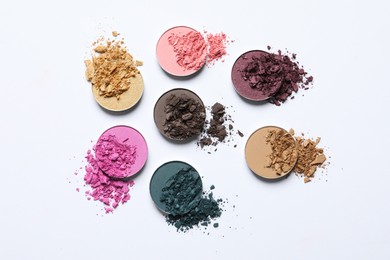 Photo of Different crushed eye shadows on white background, flat lay. Professional makeup product