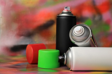 Photo of Cans of different graffiti spray paints on color background
