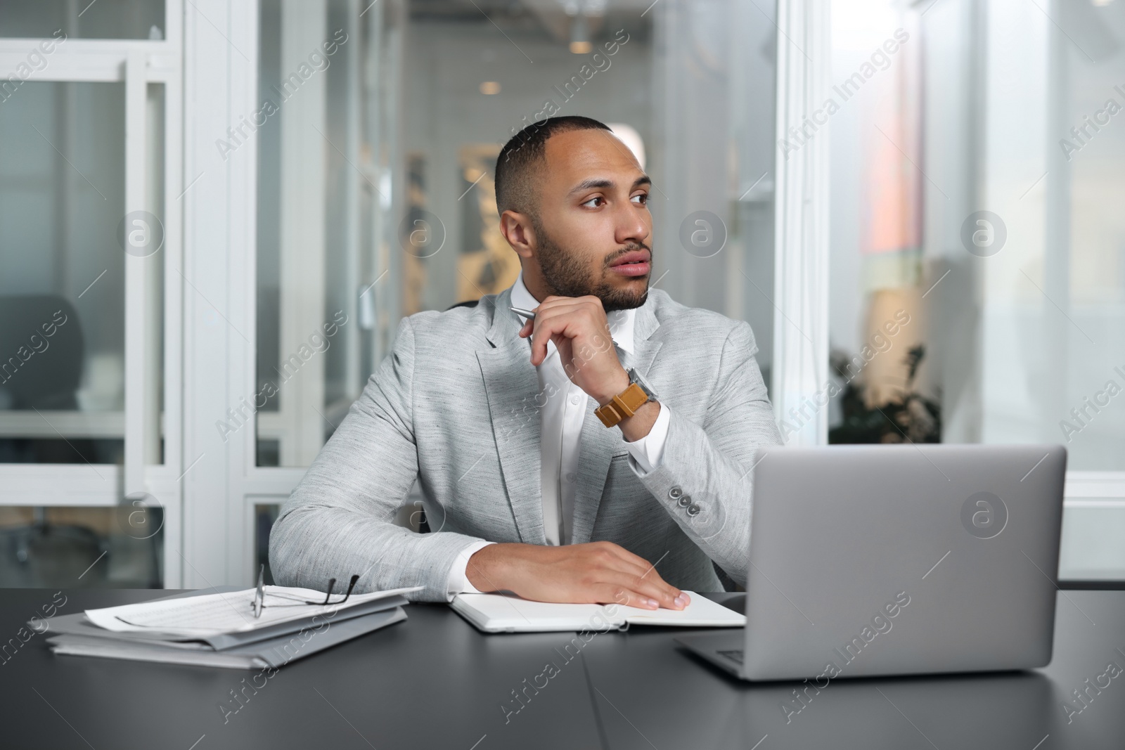 Photo of Thoughtful man working at table in office. Lawyer, businessman, accountant or manager