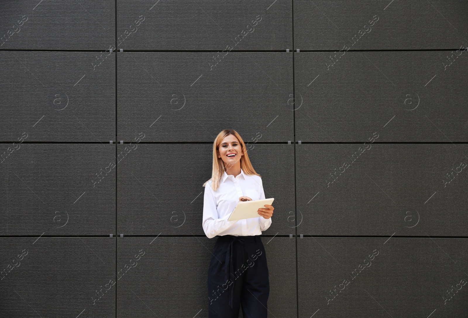 Photo of Female real estate agent with tablet near dark wall
