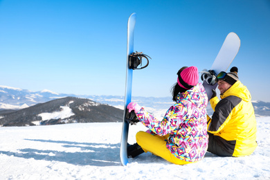 Couple with snowboards on hill, space for text. Winter vacation