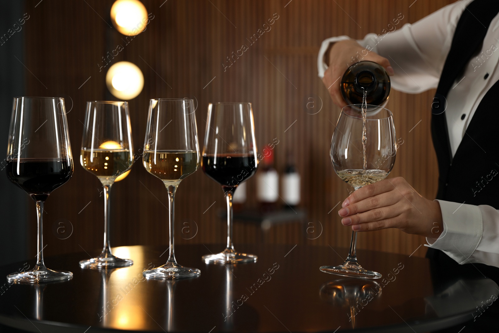 Photo of Waitress pouring wine into glass in restaurant, closeup