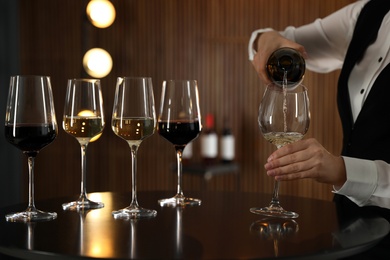 Waitress pouring wine into glass in restaurant, closeup