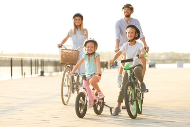 Photo of Happy family riding bicycles outdoors on summer day