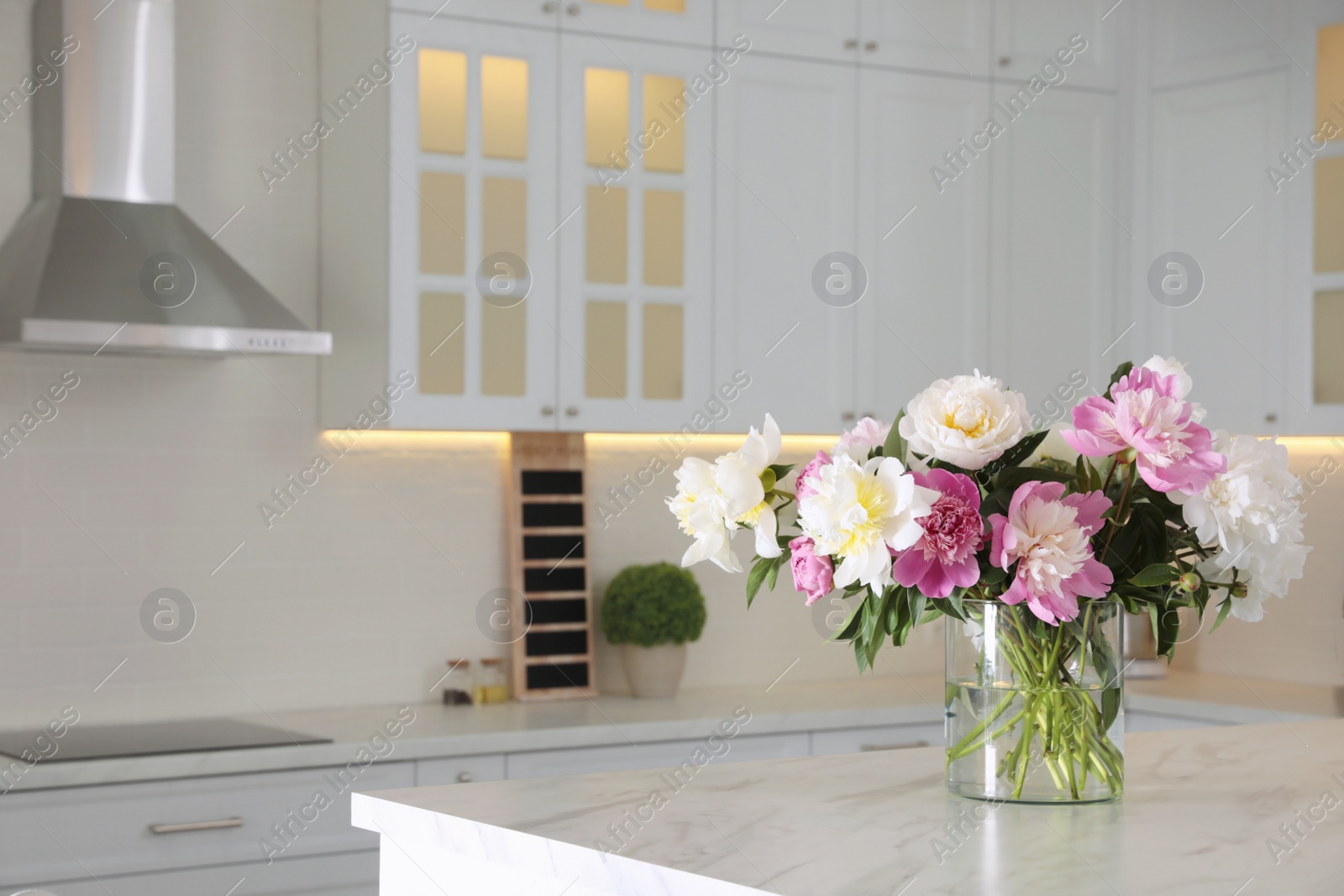 Photo of Bouquet of beautiful peonies on table in modern kitchen. Interior design