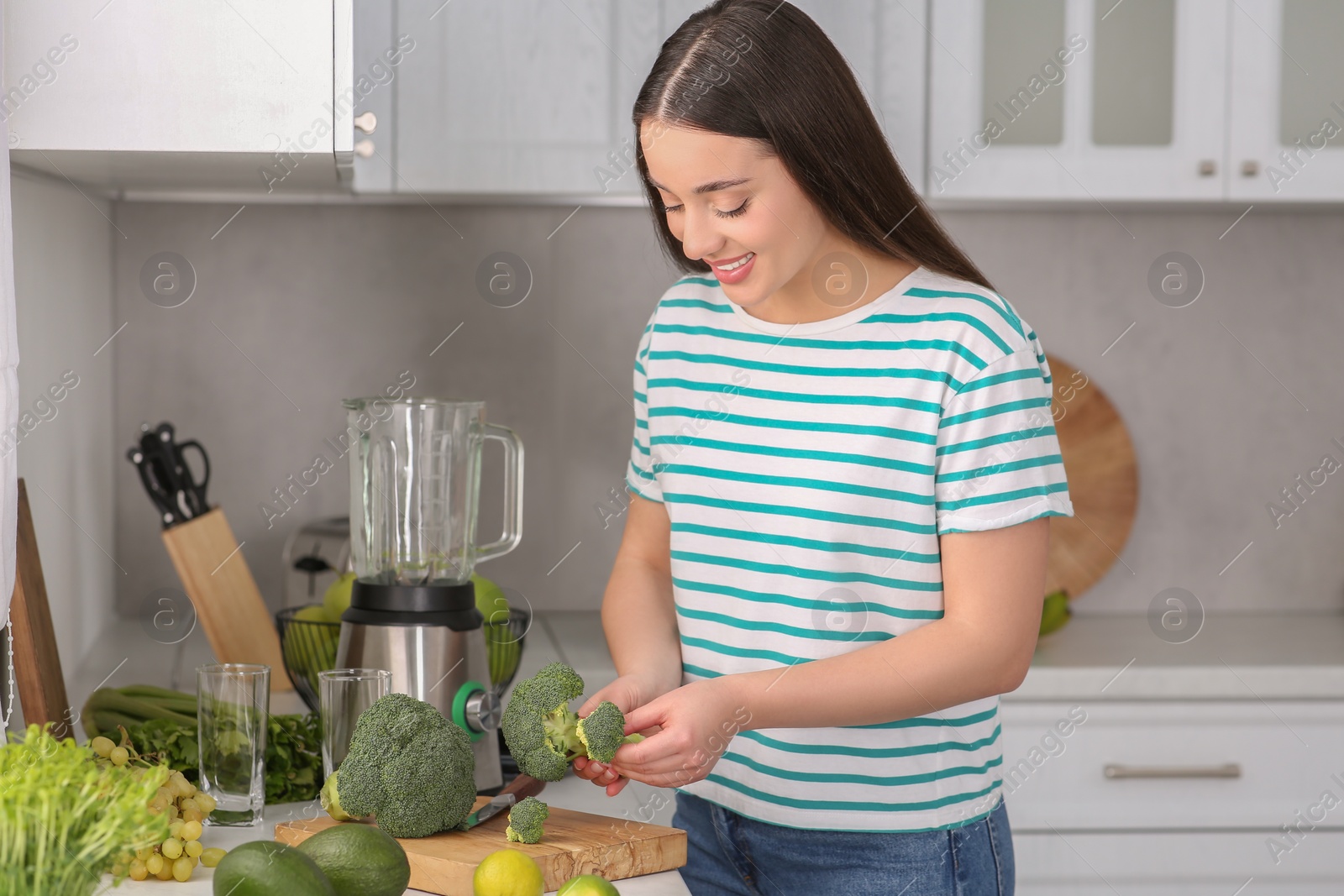 Photo of Beautiful young woman with broccoli for smoothie in kitchen