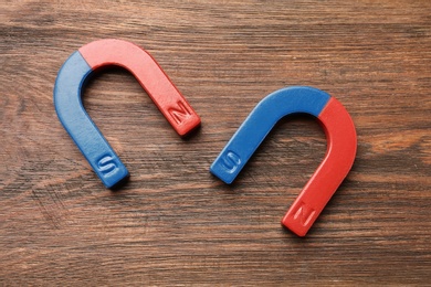 Photo of Red and blue horseshoe magnets on wooden background, top view