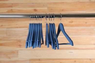 Metal rack with clothes hangers on wooden background