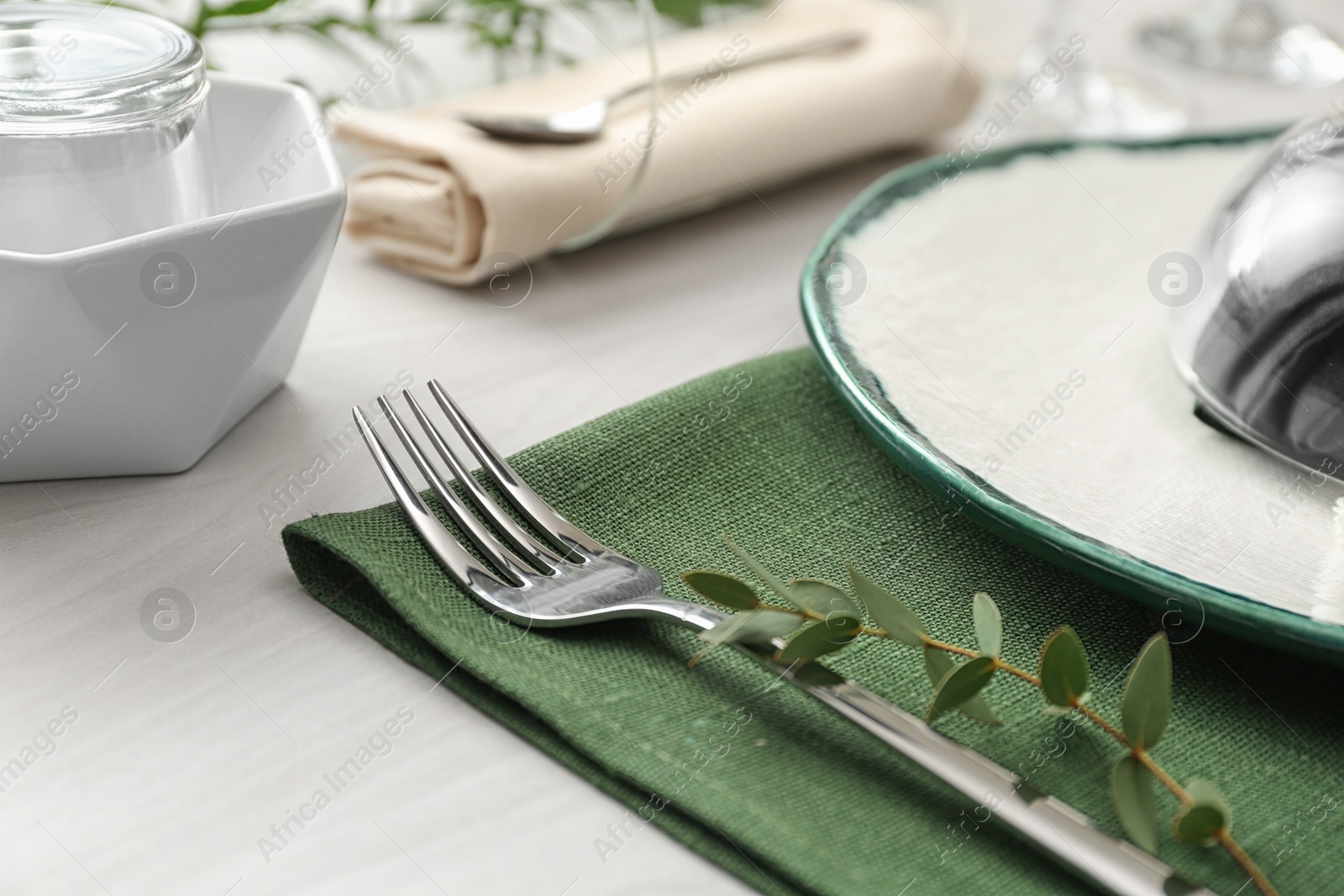 Photo of Stylish clean fork with leaves on white table, closeup. Festive setting