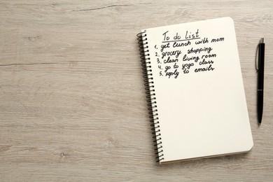 Notebook with to do list and pen on white wooden table, flat lay. Space for text