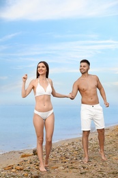 Photo of Young woman in bikini with her boyfriend on beach. Lovely couple