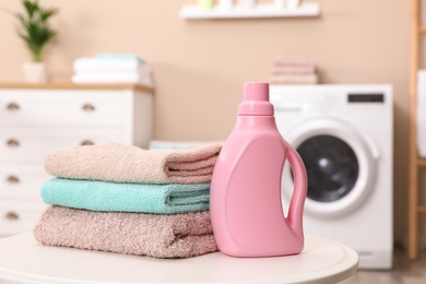 Photo of Stack of towels and detergent on table against blurred background