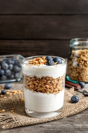 Glass with yogurt, berries and granola on wooden table